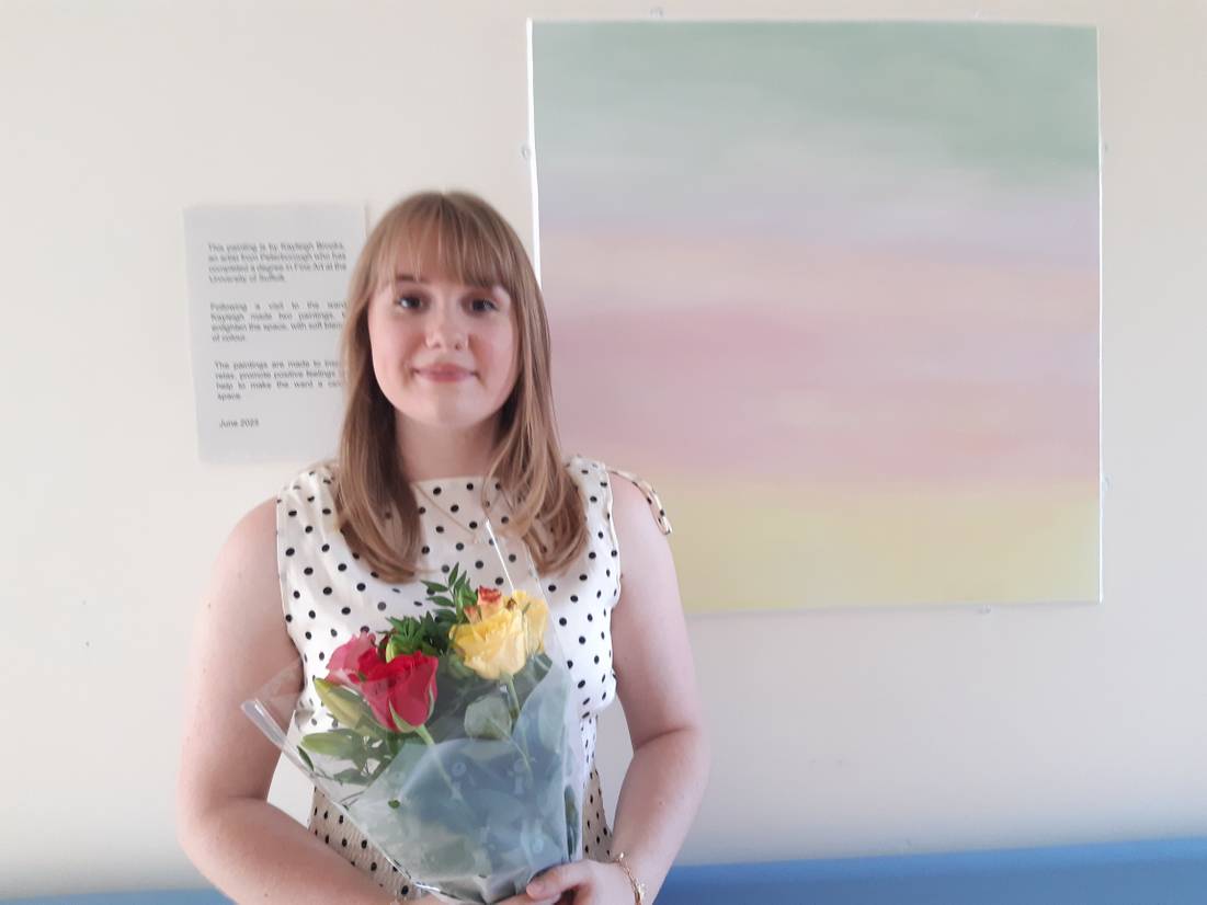 Kayleigh Brooks standing with one of her artworks created for the mental health wards at Ipswich Hospital