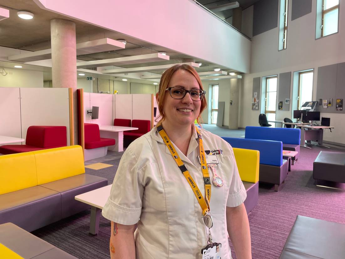 Kelly White, a student who came through Clearing, standing on the first floor of the Waterfront Building with study booths visible behind