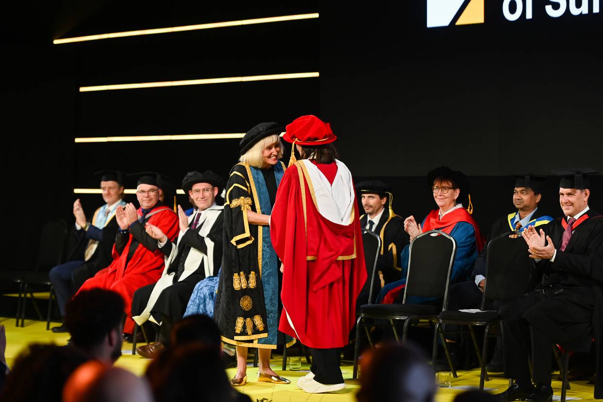 Emma Freud (right) shaking hands with Vice-Chancellor professor Jenny Higham on stage at the graduation ceremony. They are both dressed in graduation robes