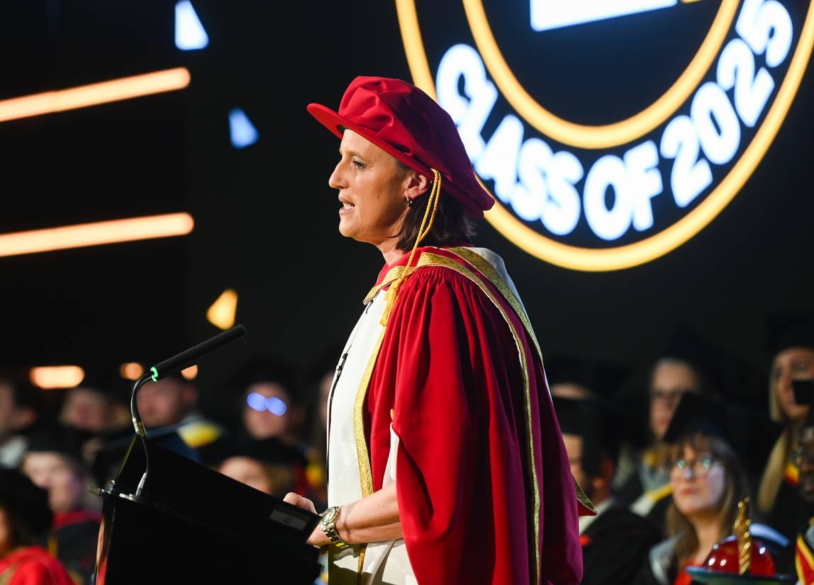 Karen Pickering dressed in her graduation robes, addressing the audience at her ceremony.