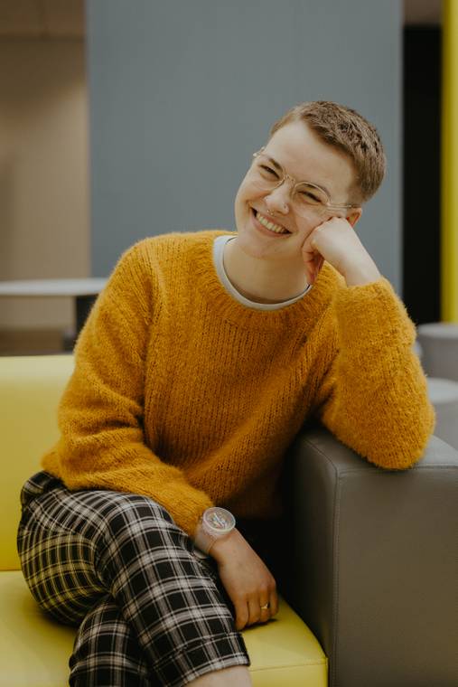 A graduate sitting down smiling