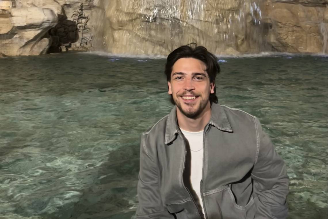 Owen Slattery smiling at the camera in front a fountain