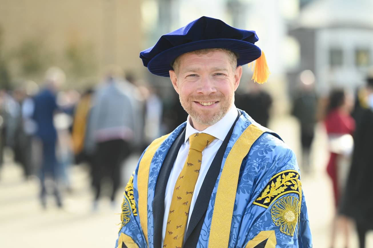 Zeb Soanes dressed in his new Chancellor robes standing on Ipswich Waterfront