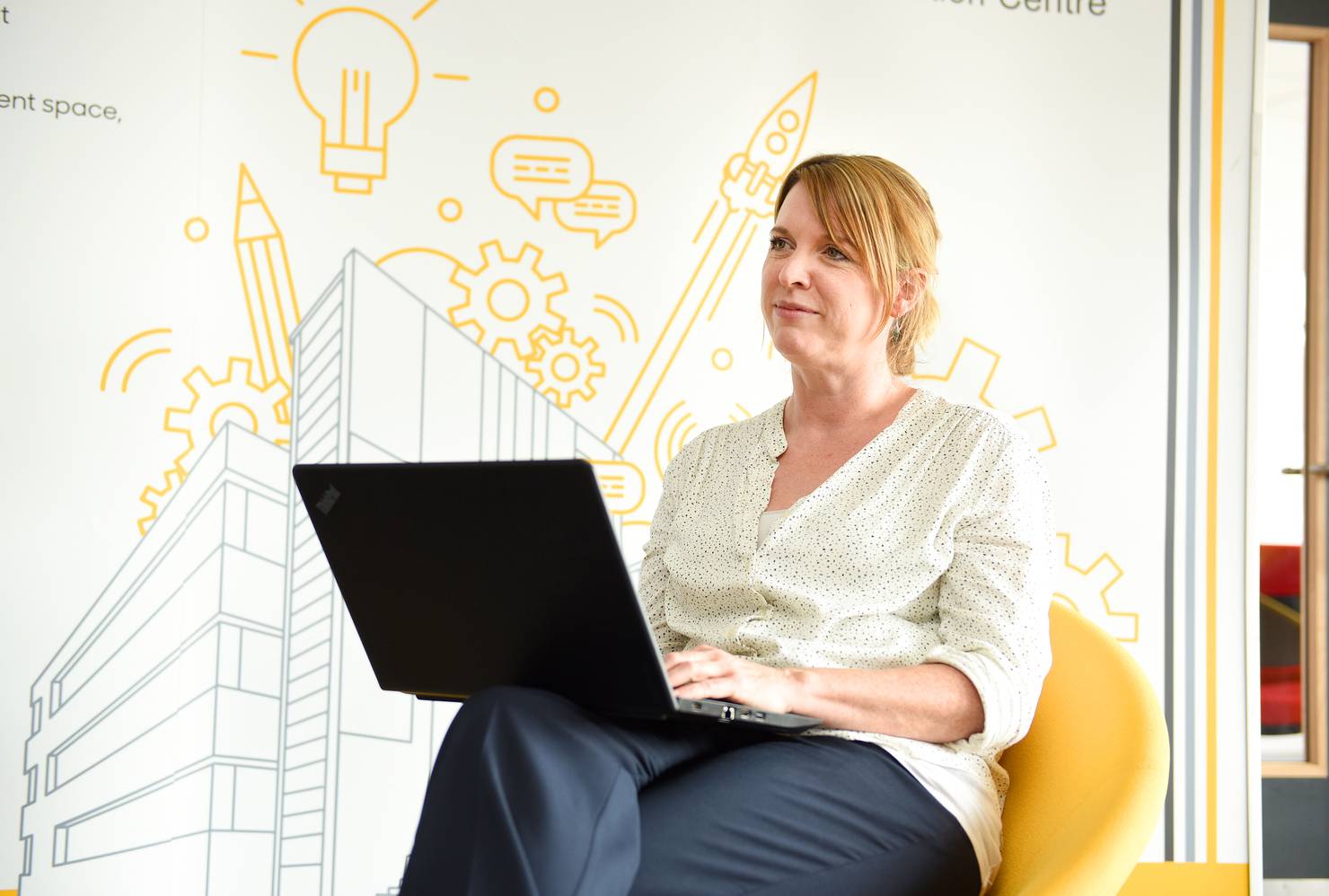 A member of staff listening in front of a mural representing ideas