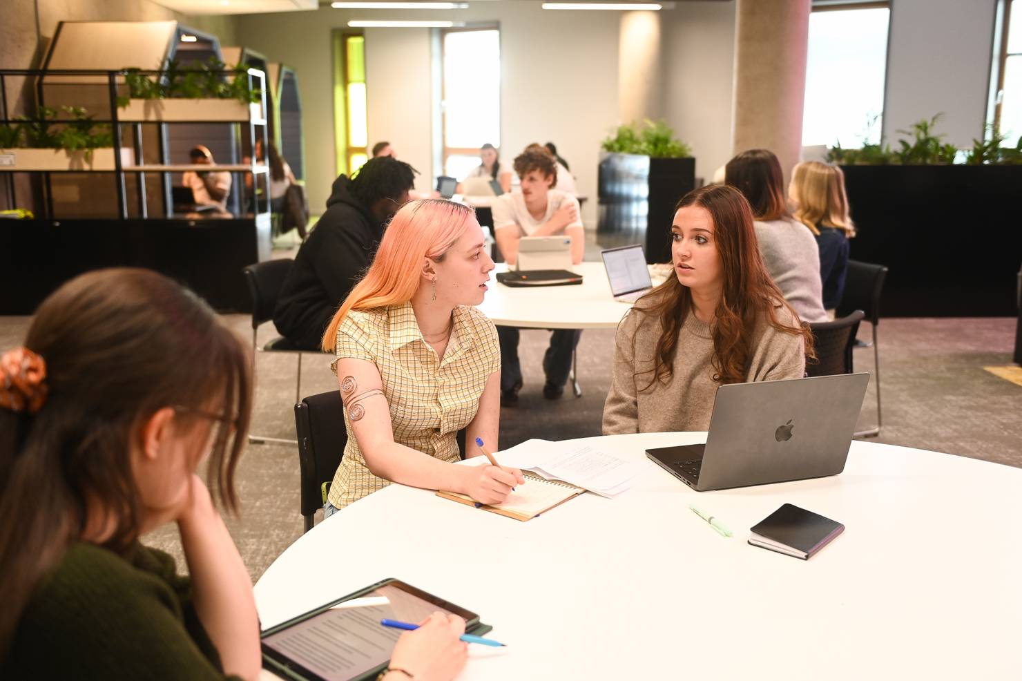 Students seated around a table in the Library, chatting through some group work