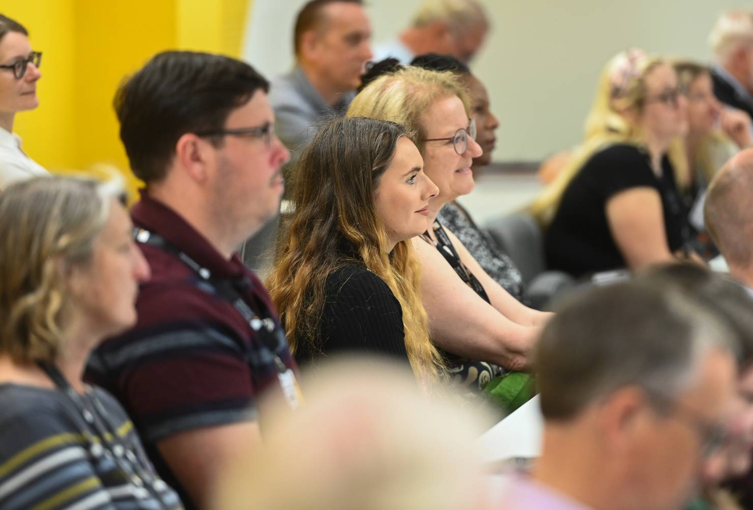 Members of an audience seated in a lecture theatre and listening to a speaker