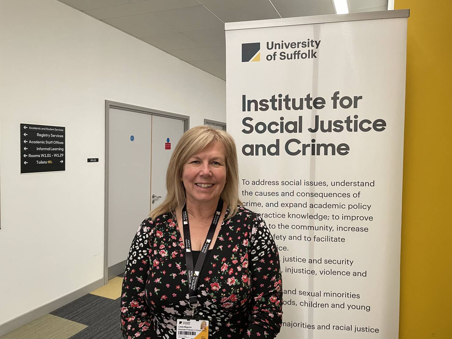 Linda Maguire standing next to the sign which says Institute for Social Justice and Crime