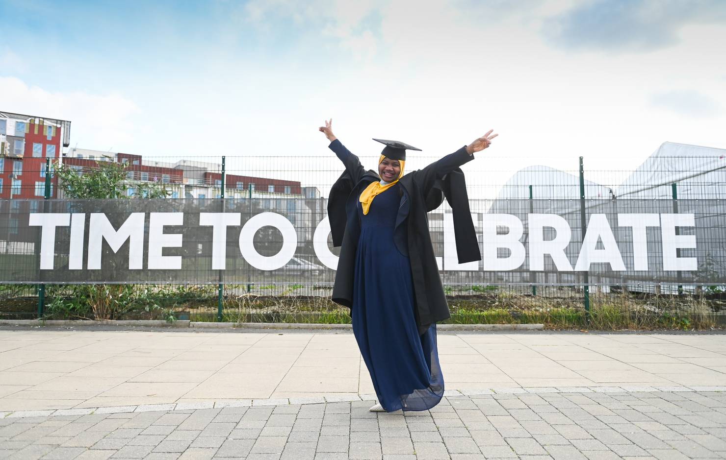 A student throws her arms in the air to celebrate graduation