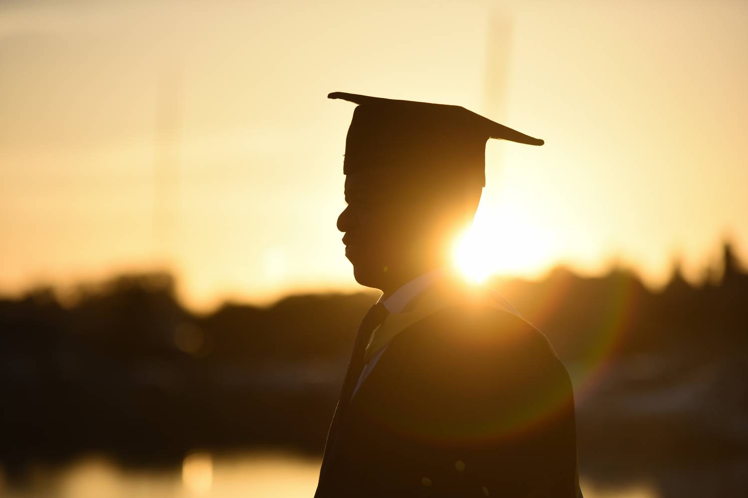 A silhouette of a student in their cap and gown