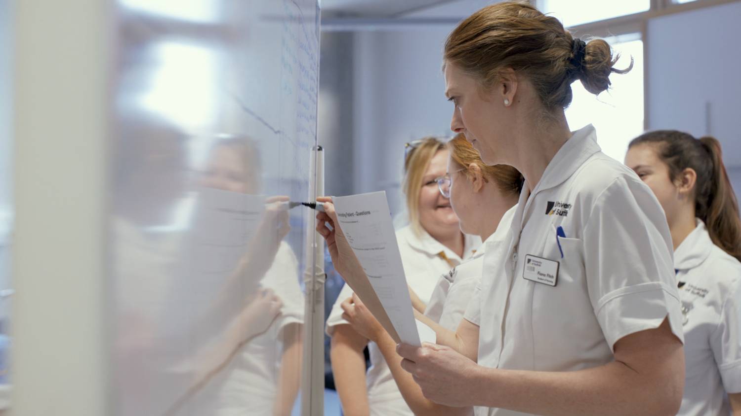 A student nurse writing on a whiteboard