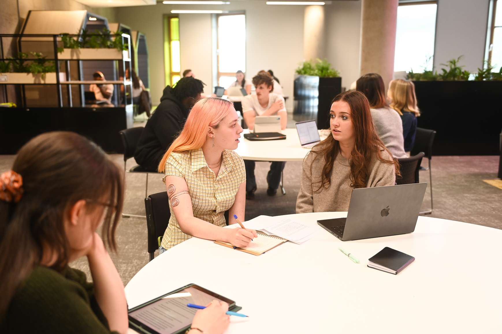 Students seated around a table in the Library, chatting through some group work