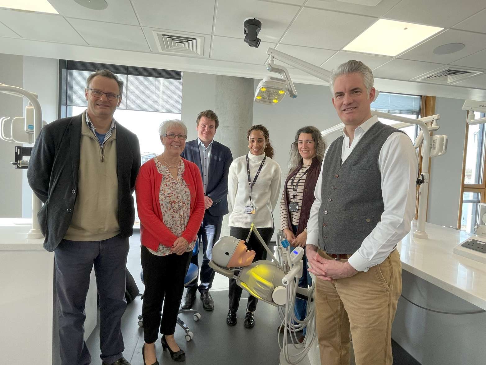 A photo of Suffolk MPs Peter Aldous, Tom Hunt and James Cartlidge with Vice Chancellor Helen Langton and dentistry lecturer Stacianne Tennant. The group are gathered around a dentistry mannequin in the labs