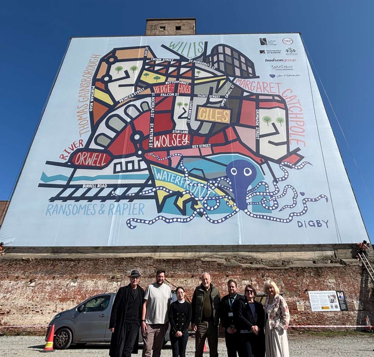 The Ipswich map artwork mural on the side of the Paul's silo building on Ipswich Waterfront. A group of those involved stand in front of the new artwork