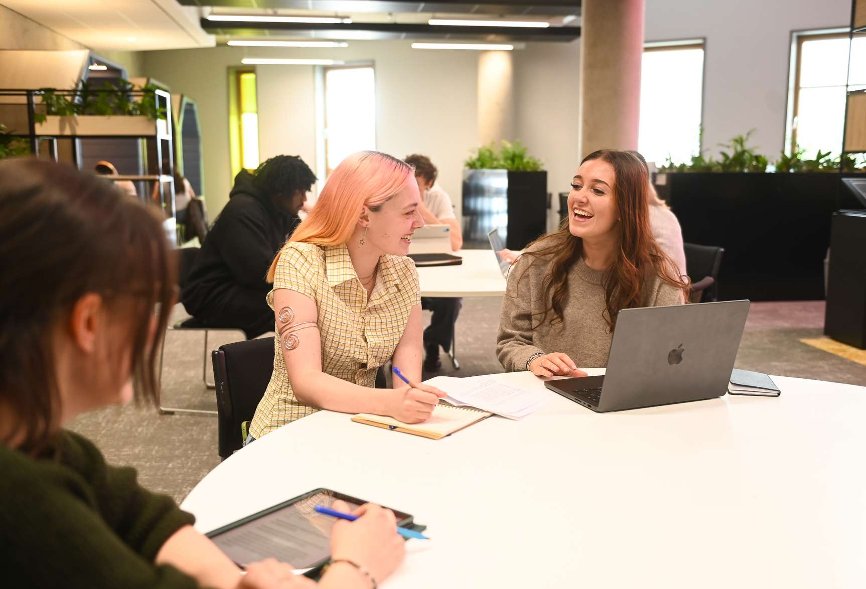 A group of three students in the library working together and smiling