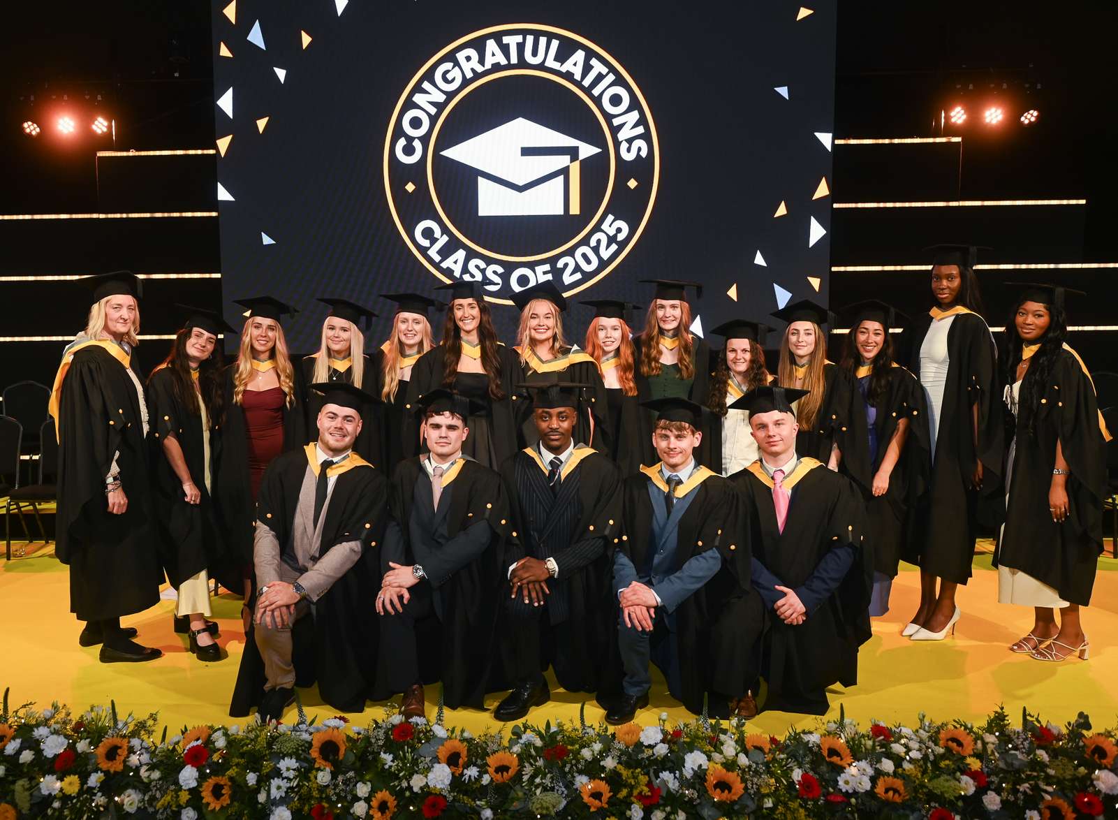 The first graduating Physiotherapy students dressed in their graduation robes and standing on the stage