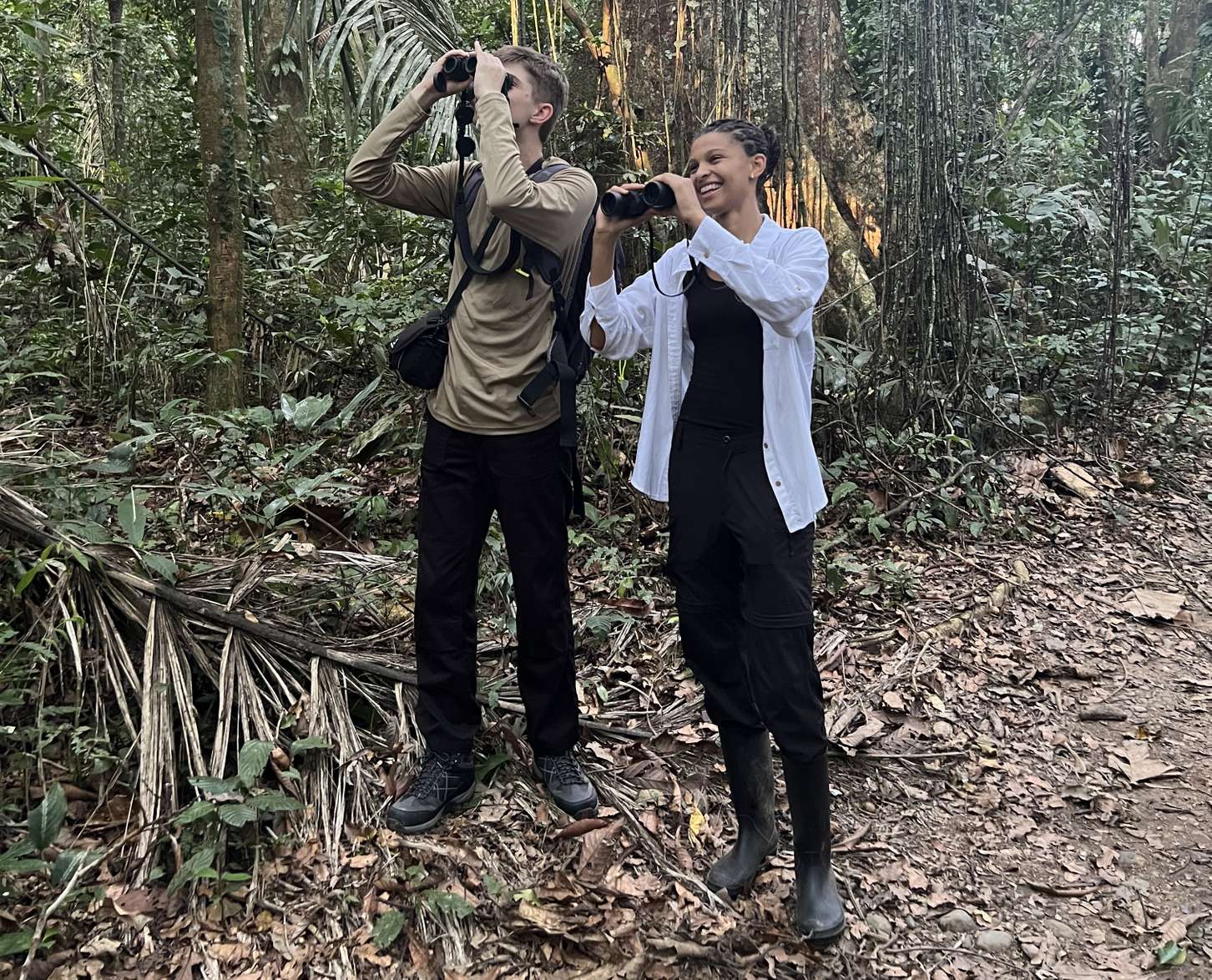 Students dan Beckett and Leyla Huo in the Amazon. They are looking into the sky through binoculars