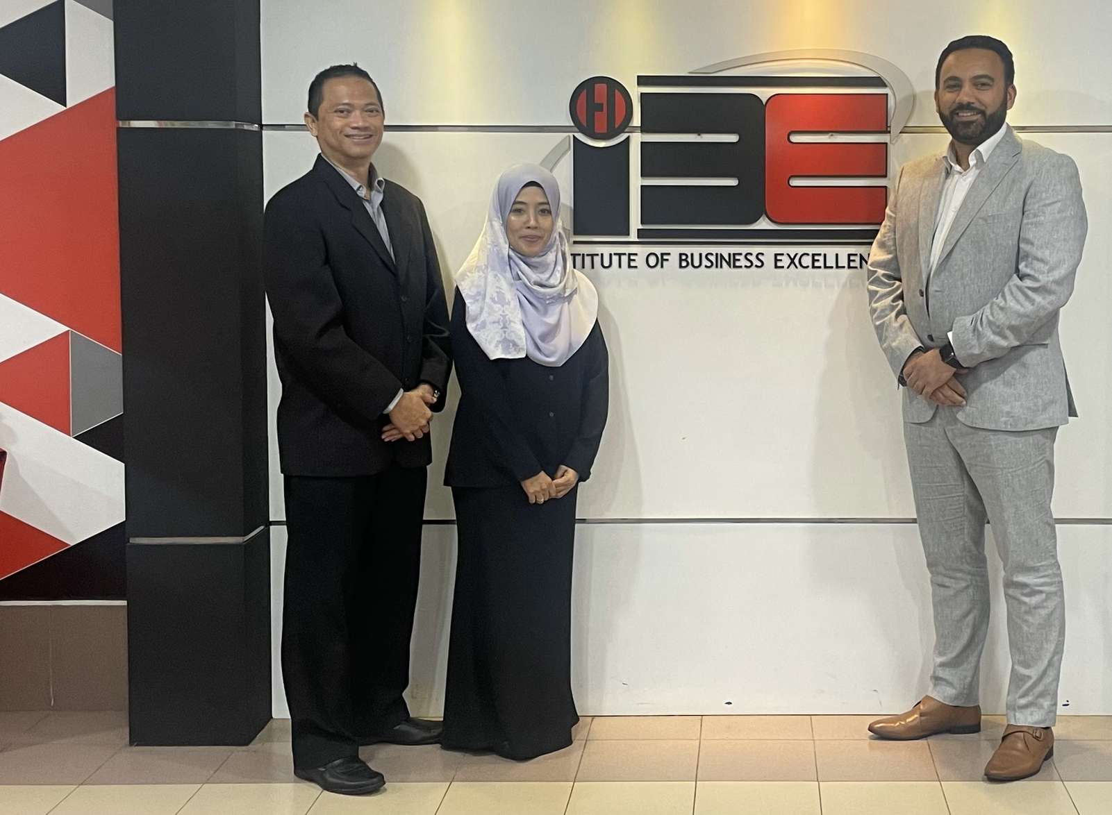 Partners from ChangeSchool, UiTM and the University of Suffolk standing by a sign that says Institute of Business Excellence