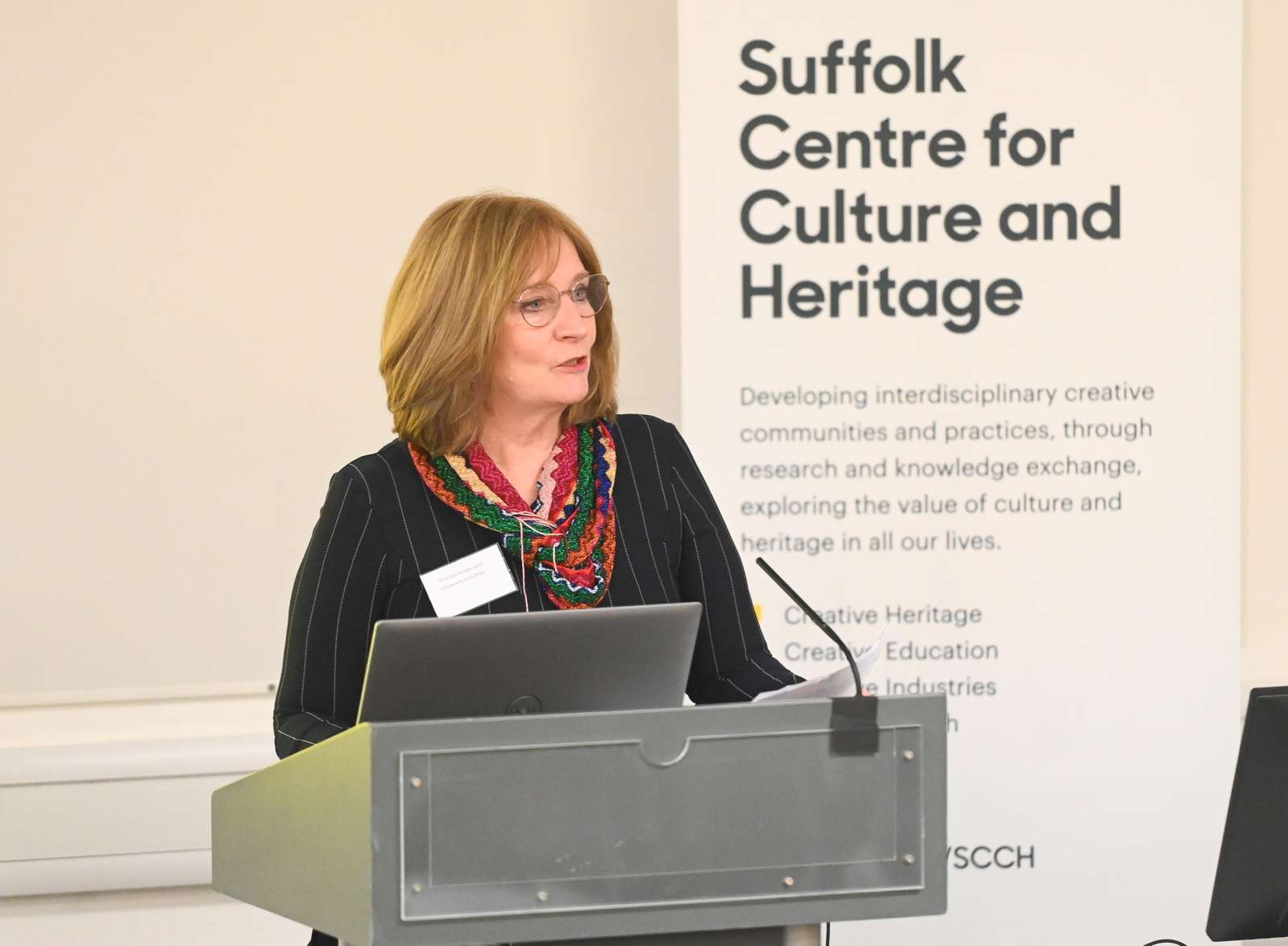 Dr Amanda Hodgkinson standing at a lectern and addressing the audience at the launch of the new Suffolk Centre for Culture and Heritage. behind her is a banner which says 'Suffolk Centre for Culture and Heritage'