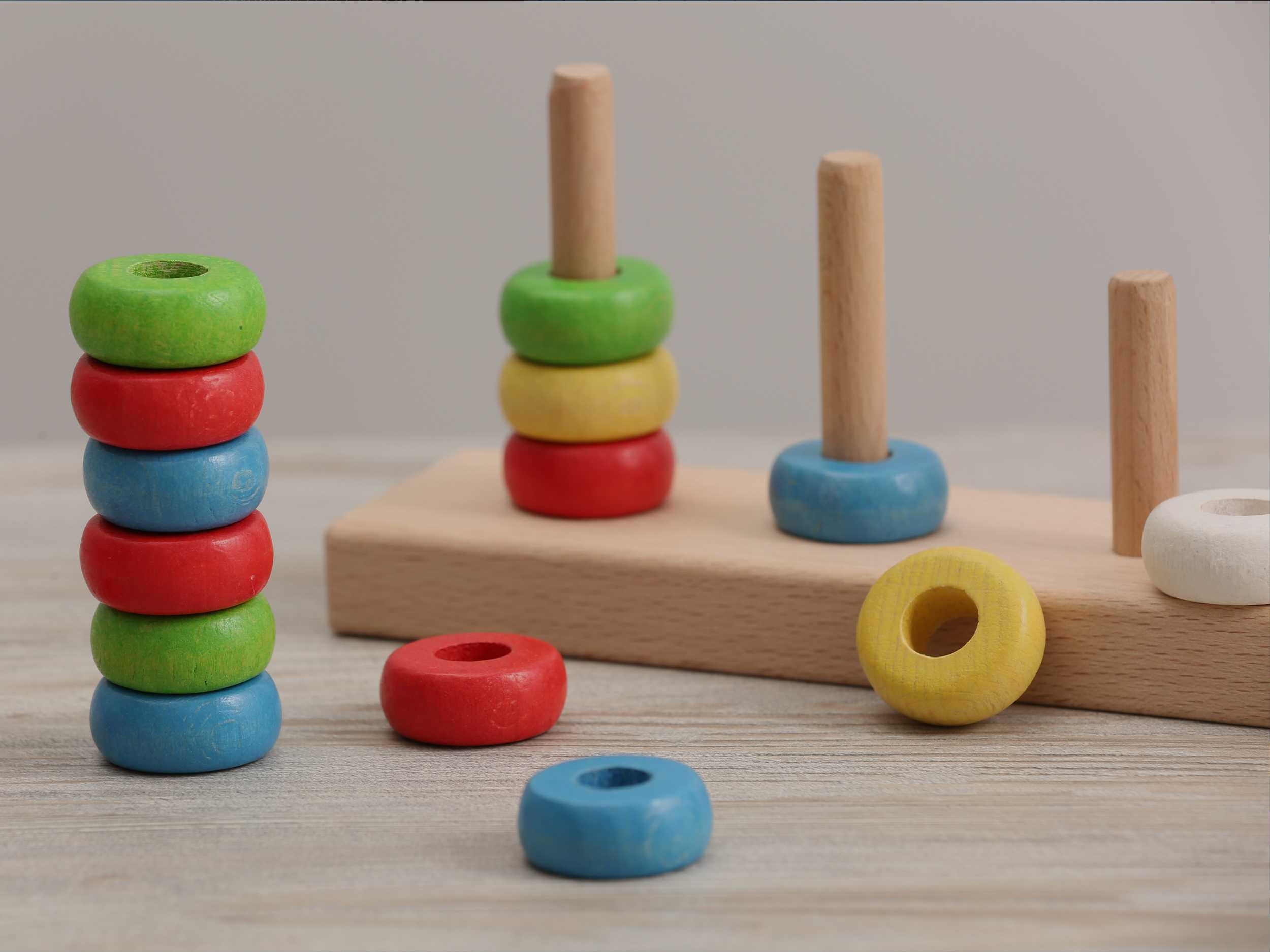 Educational toy for motor skills development. Stacking and counting game pieces on light wooden table