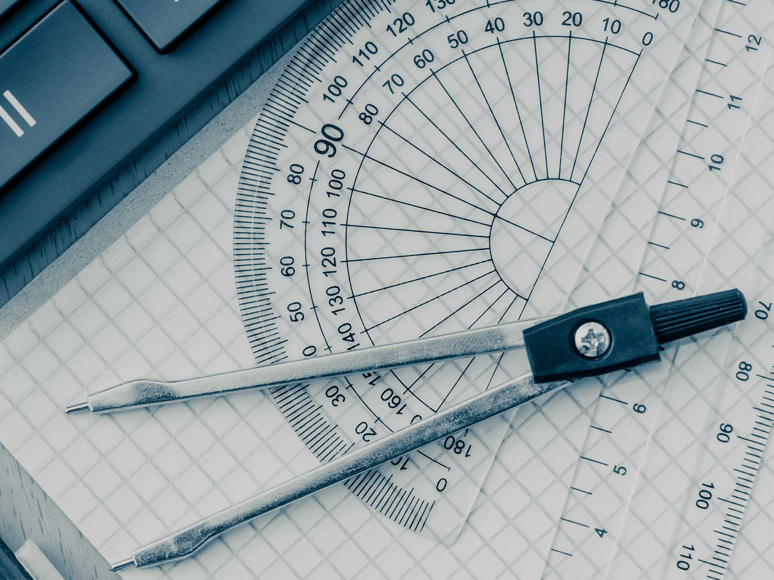 Close-up of a protractor, compass and grid paper