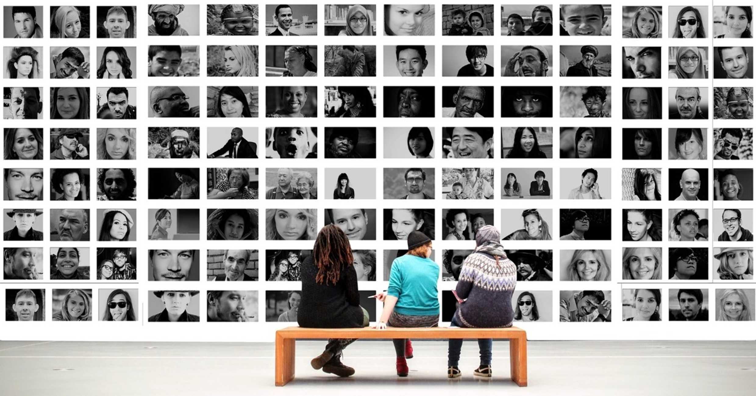 Three people looking at an image wall of diverse individuals - Sue Hollinrake