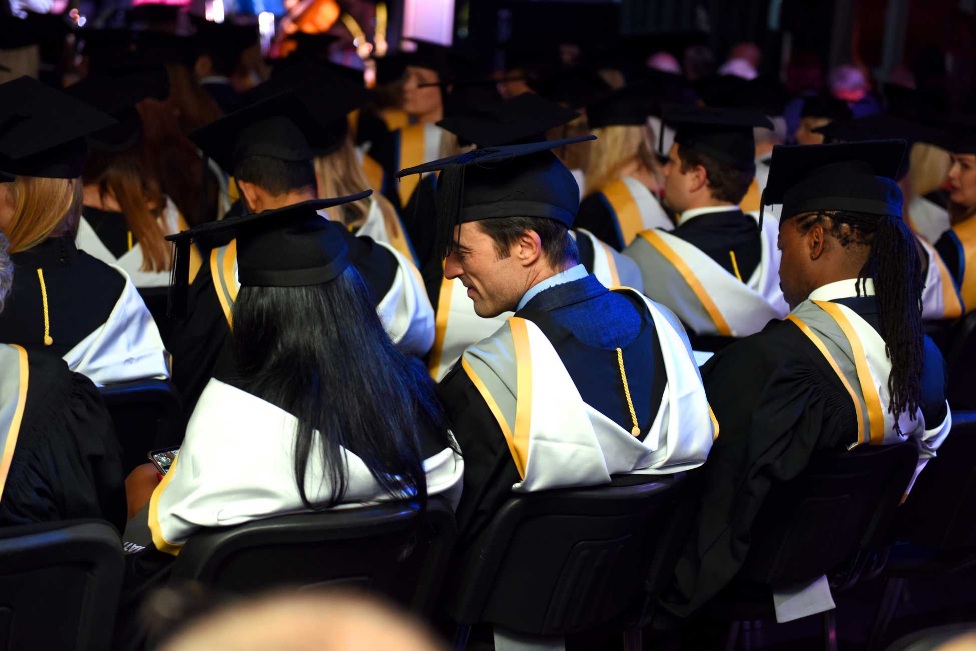 The backs of students sitting in a graduation ceremony