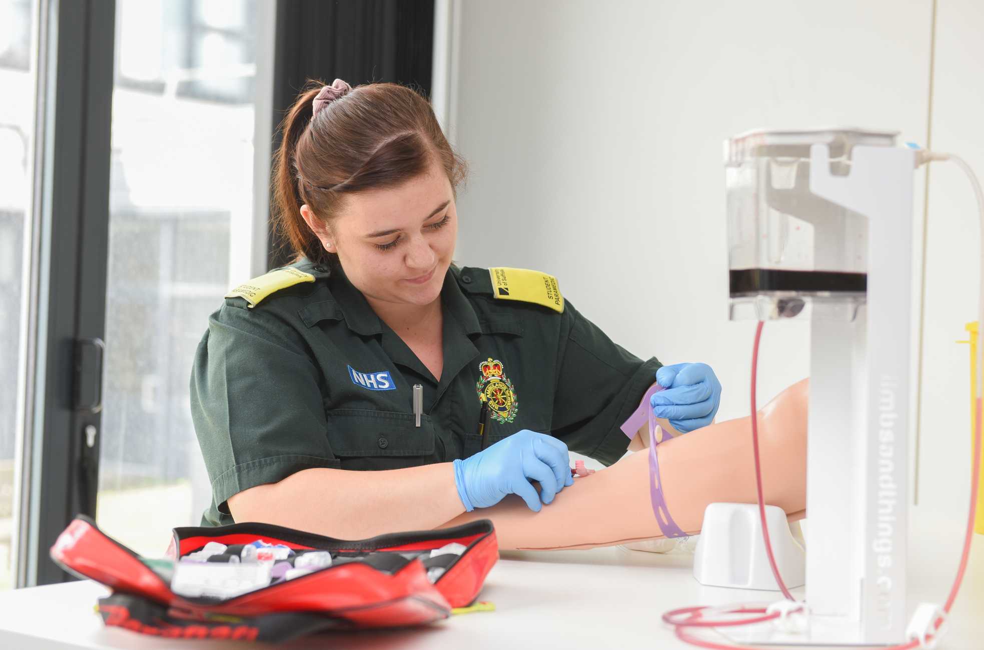 A student paramedic using phlebotomy training equipment