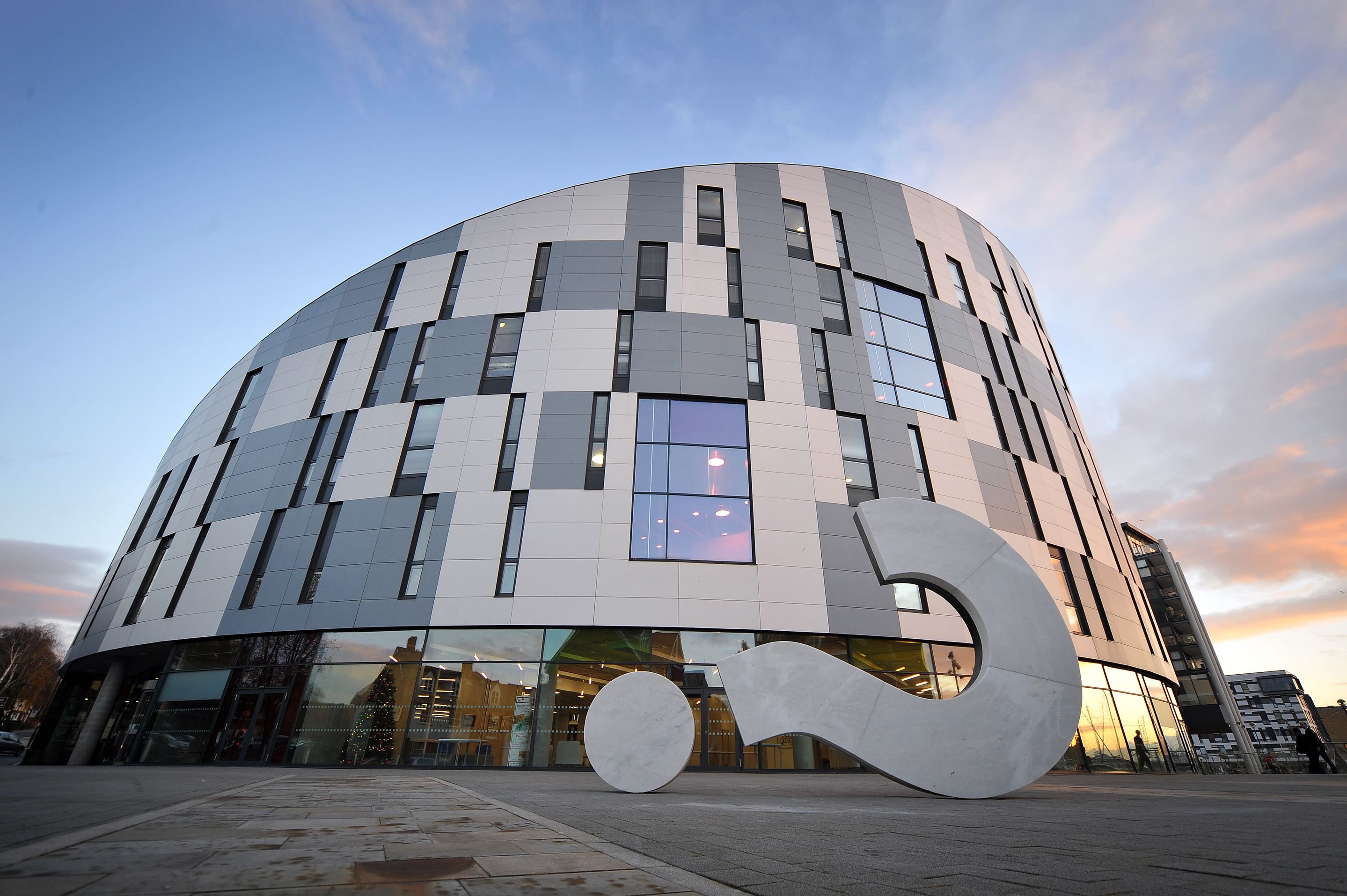 A large sculpture of a question mark outside the ipswich waterfront building at dusk