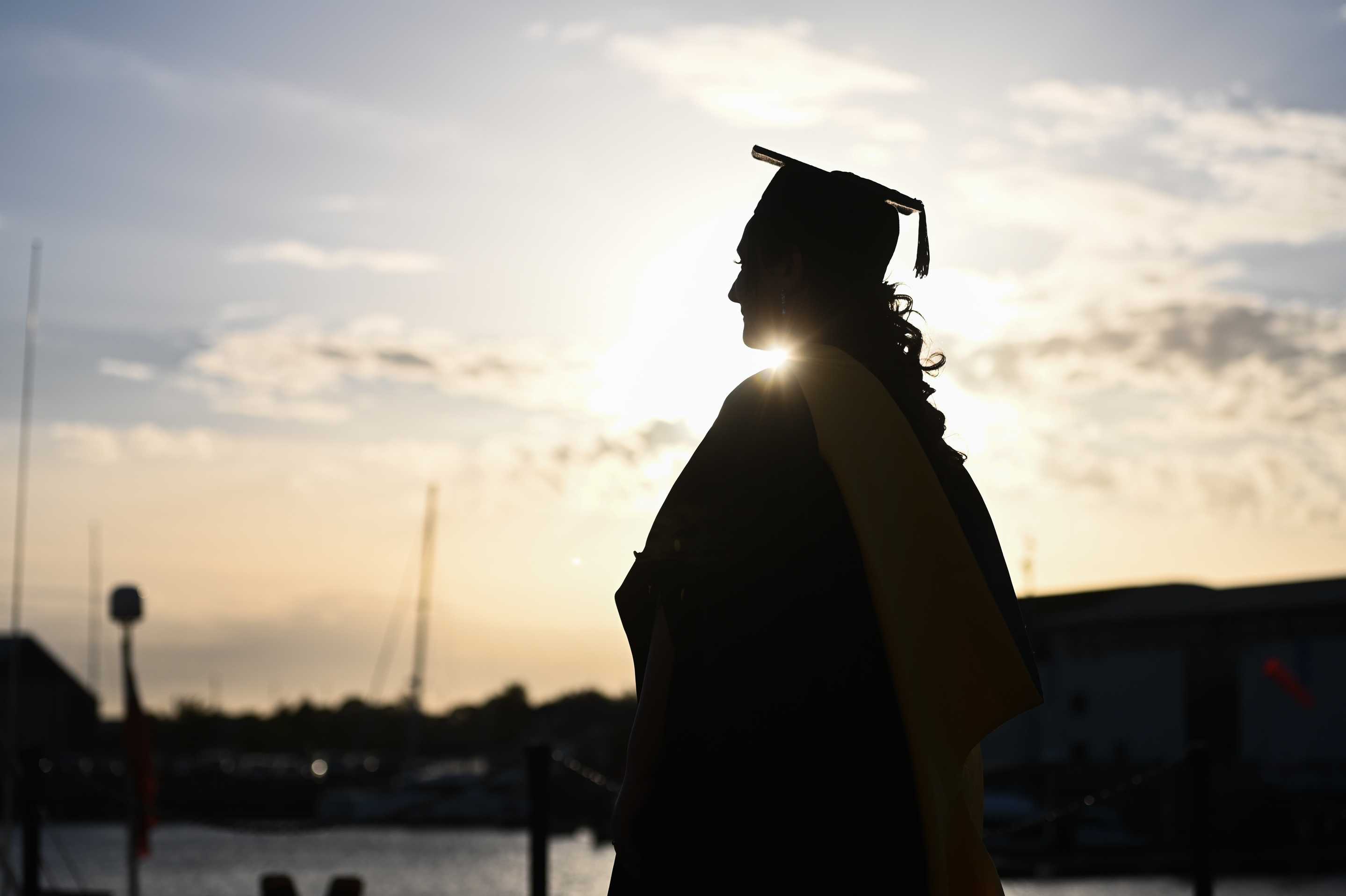 A silhouette of a student in their cap and gown