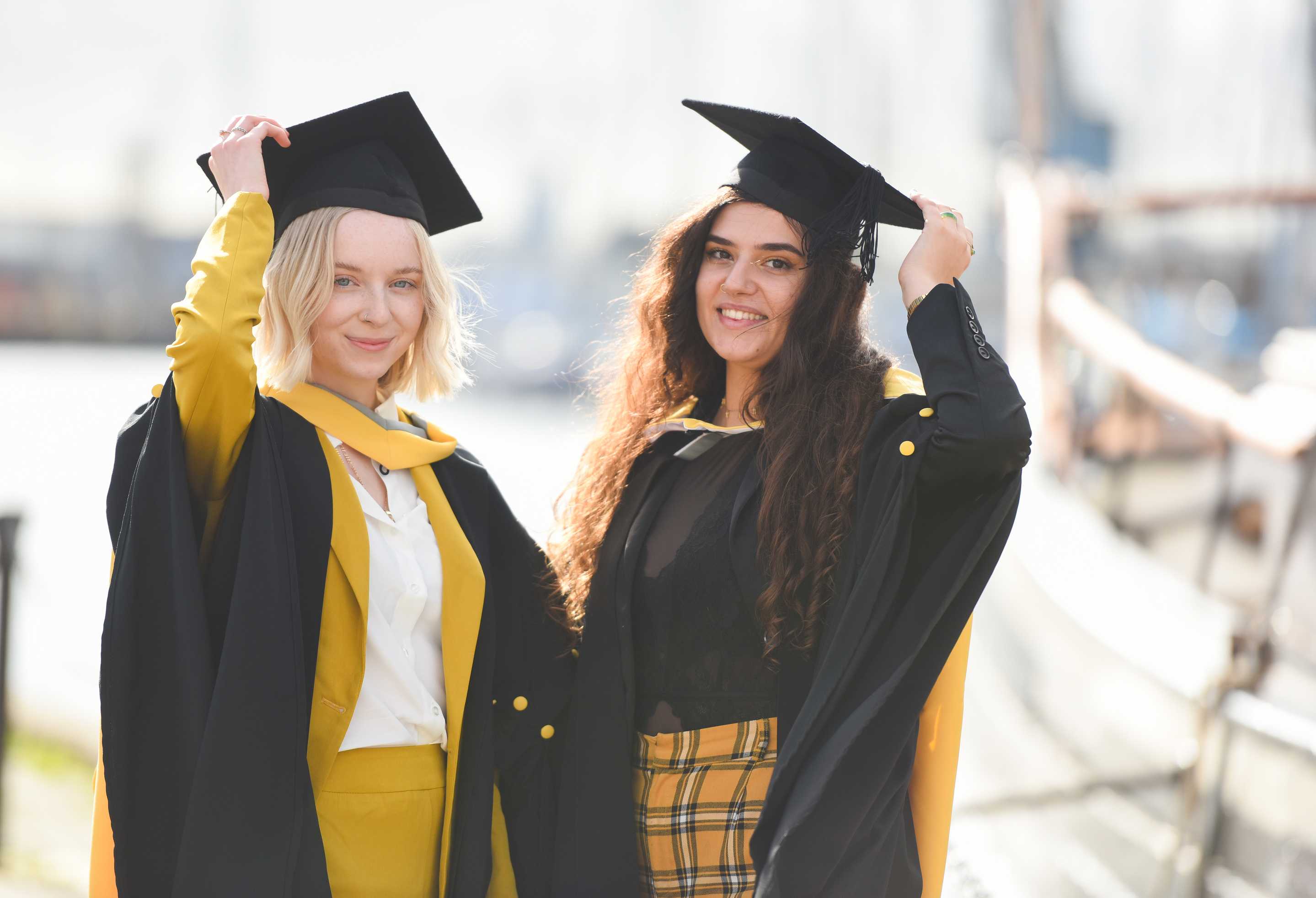 Two students holding their mortar boards
