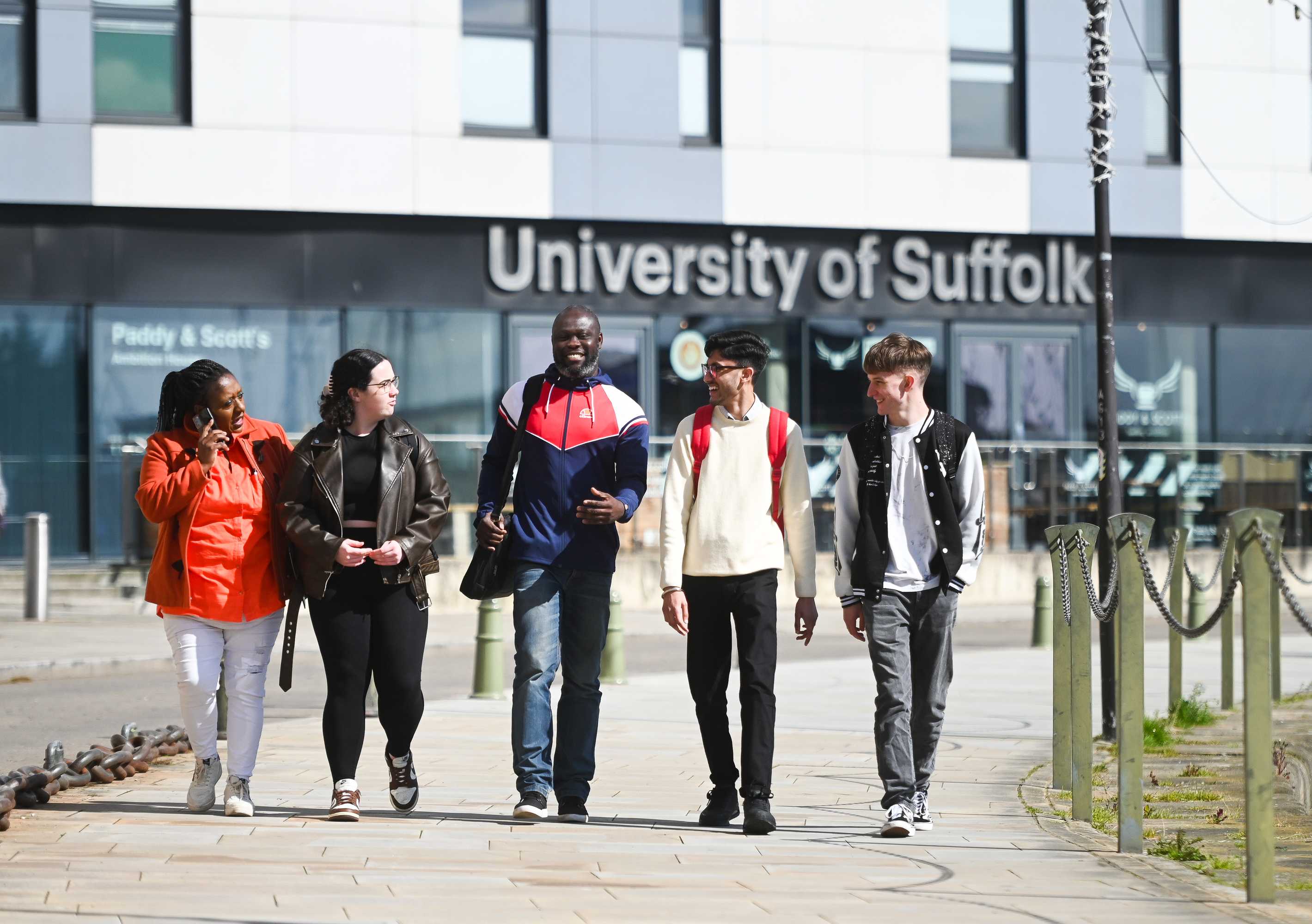 Students walking along the waterfront with the grey and white Waterfront Building behind them