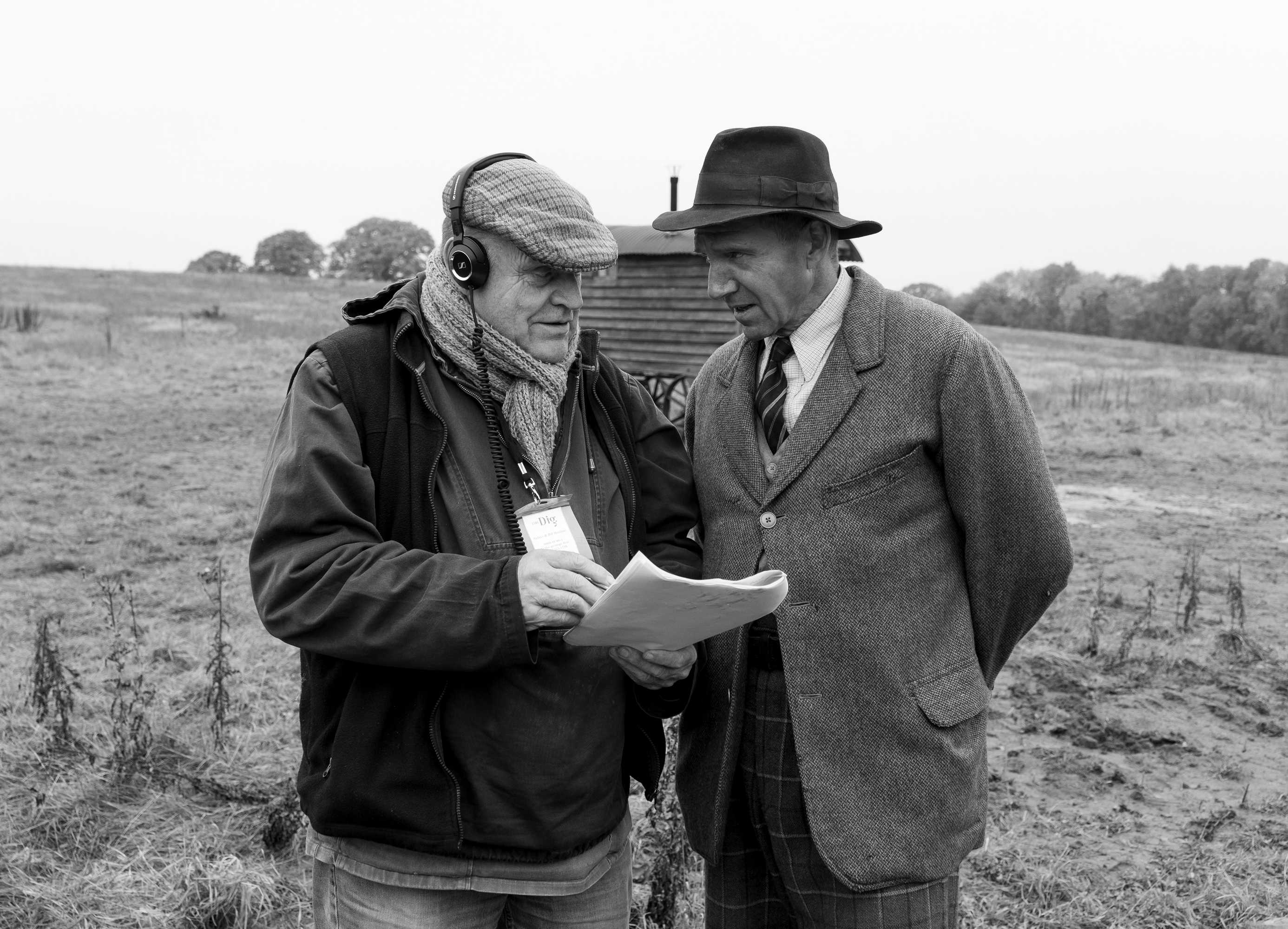 Two people standing in a field reading a script