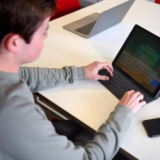 A student sitting at a desk with a tablet