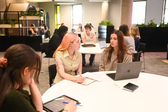 Students seated around a table in the Library, chatting through some group work