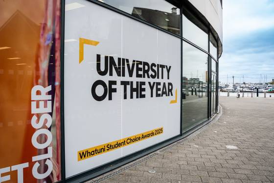 The Waterfront Building at the University of Suffolk with a 'University of the Year' sign on it from the 2025 awards win
