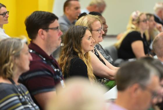 Members of an audience seated in a lecture theatre and listening to a speaker