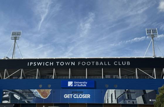 The outside of Portman Road stadium with the words 'Ipswich Town Football Club' visible. Beneath are the 鶹ý logo, image of the Waterfront Building and the words 'Get Closer'