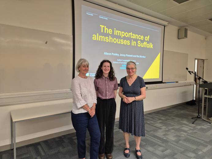 three women standing in front of a display screen in a university lecture theatre