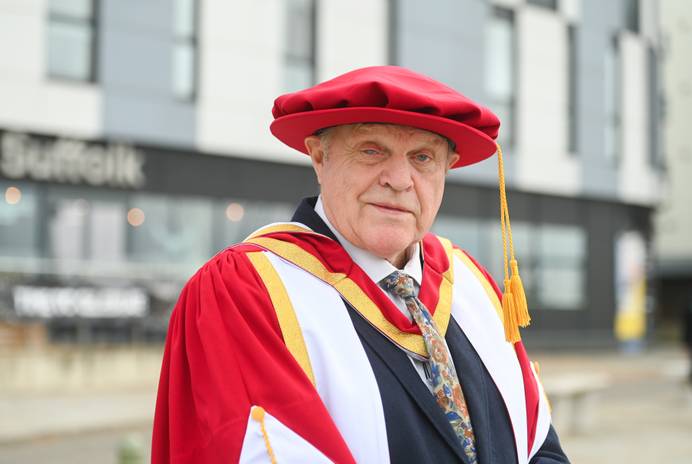 Man in graduation robes outside a university building