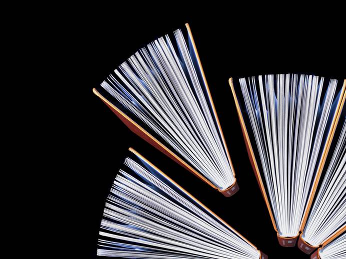 three vertically placed open books against a black background