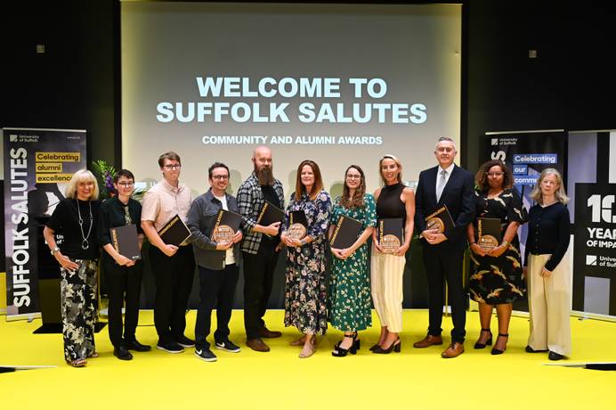 Winners of the Alumni Award and Community Award at the Suffolk Salutes 2026 event, standing on stage and holding their awards