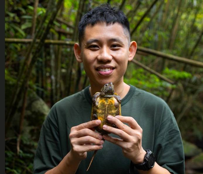 Man outdoors holding a small turtle