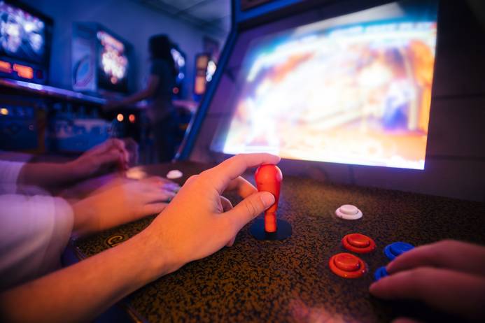 A stock image of a hand on a gaming joystick with a screen in the background