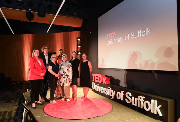 The speakers at the TEDx talk held at the University of Suffolk. The group is standing on stage with the words TEDx and University of Suffolk visible behind