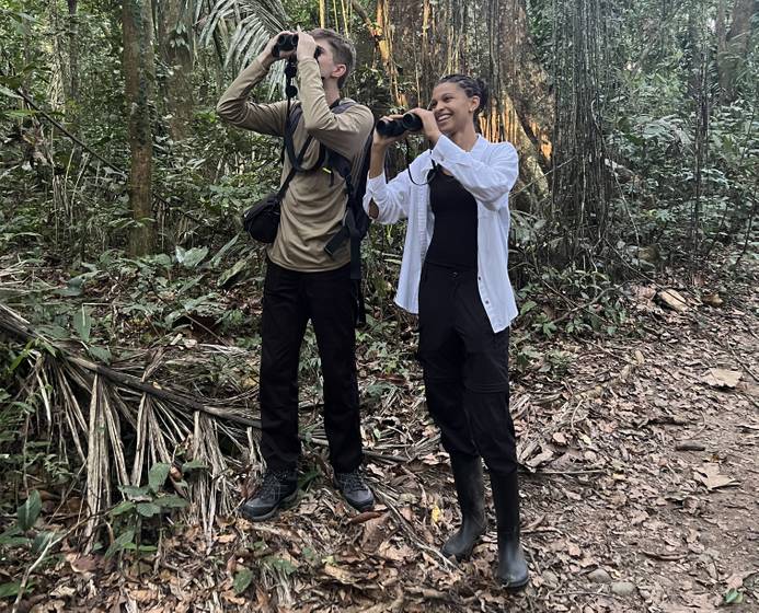Students dan Beckett and Leyla Huo in the Amazon. They are looking into the sky through binoculars