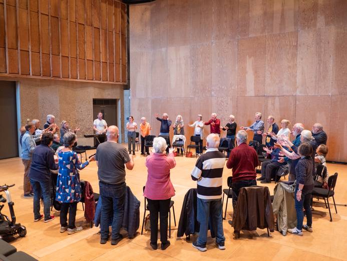 A group of participants with East Suffolk Skylarks gathered in a circle and singing