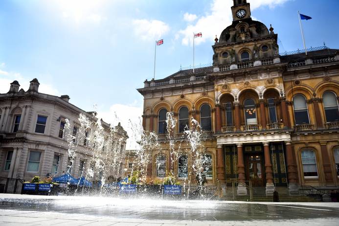 IPswich Twon Hall in the summer sunshine. The water sprinklers outside the Town Hall are on in the foreground
