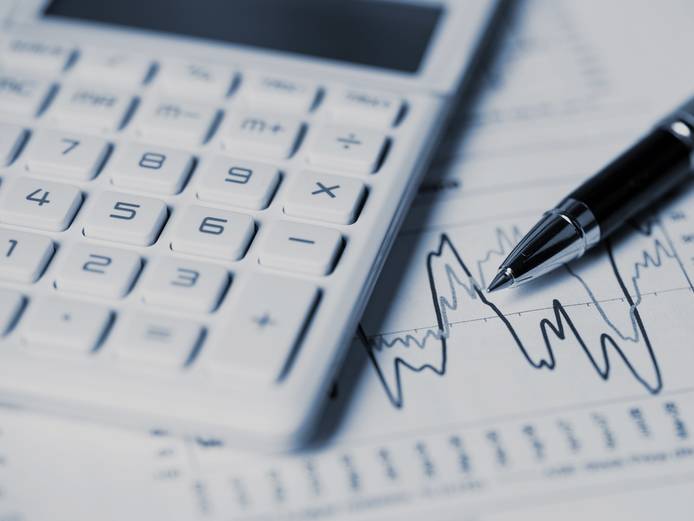 Close-up of calculator, pen and charts