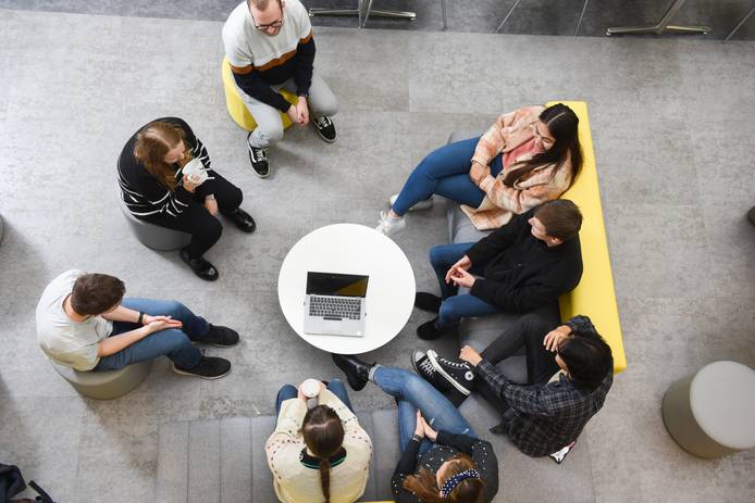 A group of students sitting and talking in The Atrium foyer