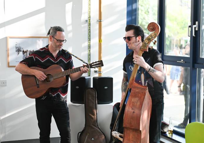 Two musicians standing playing the guitar and base